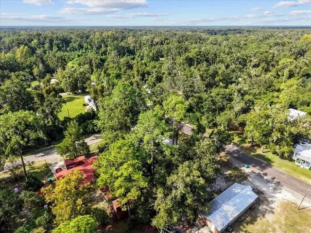 an aerial view of residential house with outdoor space and trees all around