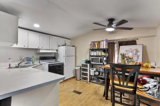 a kitchen with stainless steel appliances granite countertop a stove top oven a sink a dining table and chairs with wooden floor