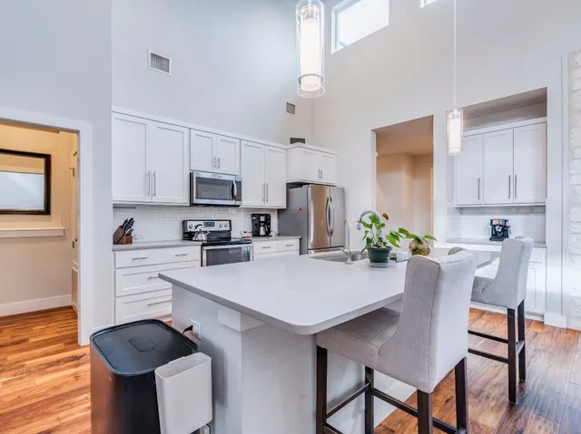 a kitchen with stainless steel appliances a stove a sink island and chairs