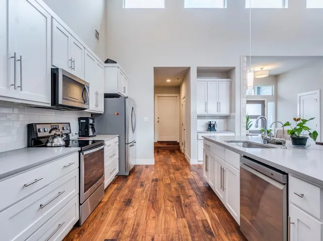 a large kitchen with stainless steel appliances granite countertop a lot of counter space and wooden floors