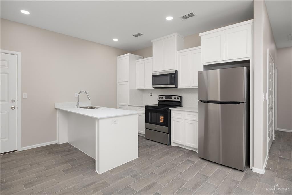 2808 West Harrison Avenue, Unit 4 Alton, TX 78573 - Photo 5 of 22 a kitchen with a refrigerator sink and white cabinets
