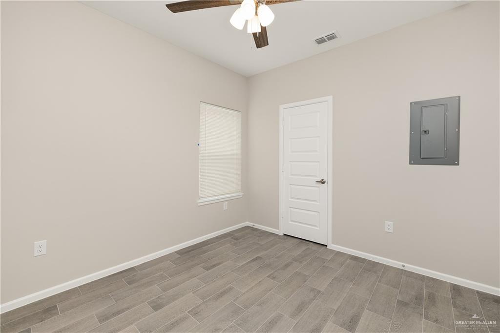 2808 West Harrison Avenue, Unit 4 Alton, TX 78573 - Photo 8 of 22 an empty room with a ceiling fan and wooden floor
