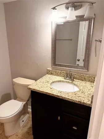 a bathroom with a granite countertop sink toilet and mirror