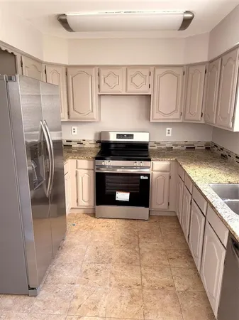 a kitchen with stainless steel appliances granite countertop a stove a sink and a refrigerator