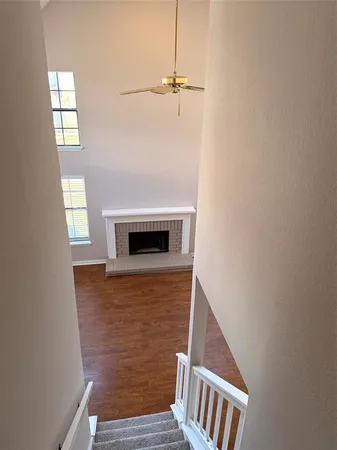 a living room with a fireplace furniture a ceiling fan and a window
