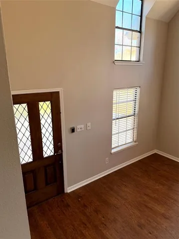 an empty room with wooden floor cabinet and windows