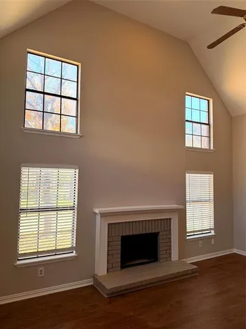 an empty room with wooden floor fireplace and windows