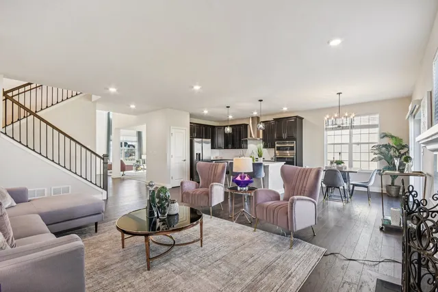 a living room with furniture kitchen view and a wooden floor