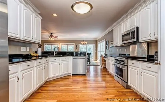 a kitchen with stainless steel appliances granite countertop a stove top oven a sink a microwave and cabinets
