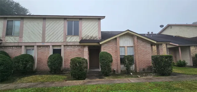 a view of a house with brick walls and a yard with plants