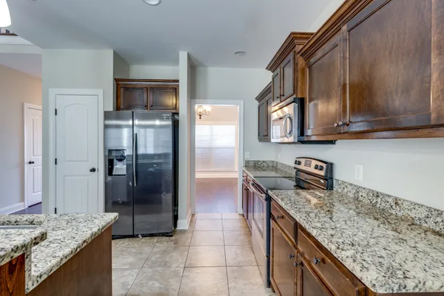 a kitchen with stainless steel appliances granite countertop a refrigerator a stove and a sink