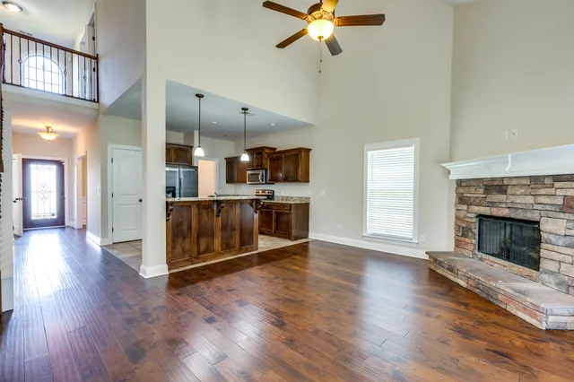 an empty room with wooden floor fireplace and windows