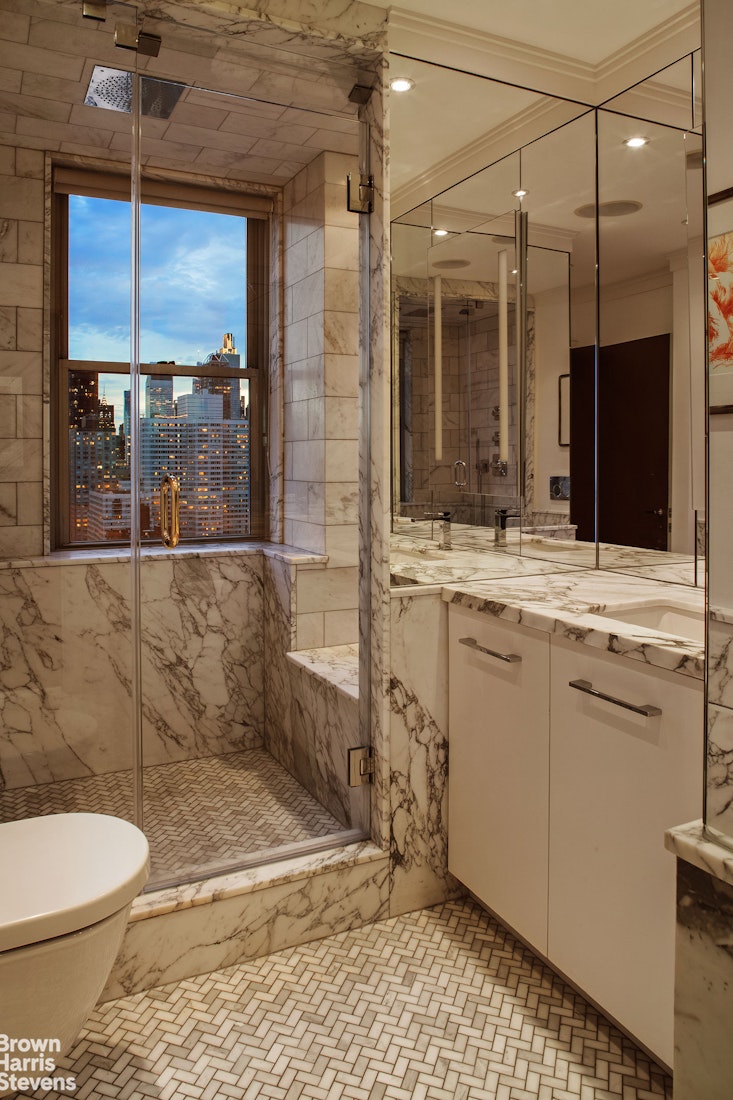 300 East 74th Street, Unit 30AB Manhattan, NY 10021 - Photo 10 of 17 a bathroom with a granite countertop sink a toilet a mirror and shower