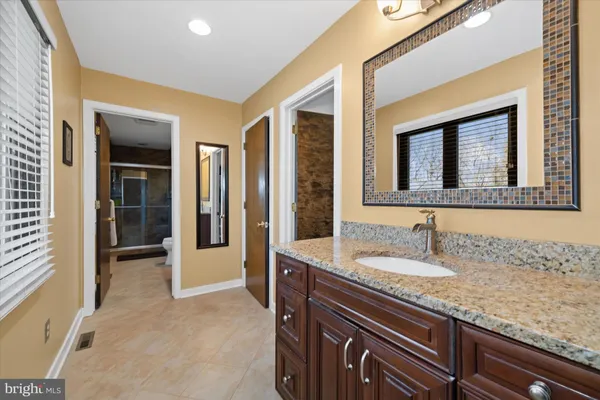 a bathroom with a granite countertop sink and a mirror