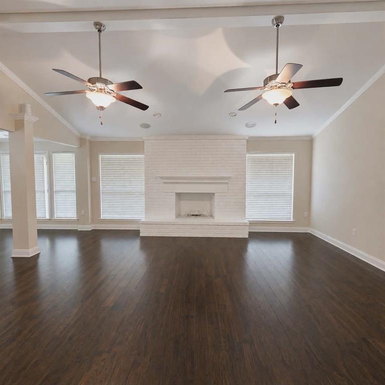 14752 Ranch Road Forney, TX 75126 - Photo 9 of 40 Spacious living area featuring dark wood-finish flooring, a white brick fireplace, multiple windows with blinds, and two ceiling fans with integrated lighting-This photo was taken before family moved in