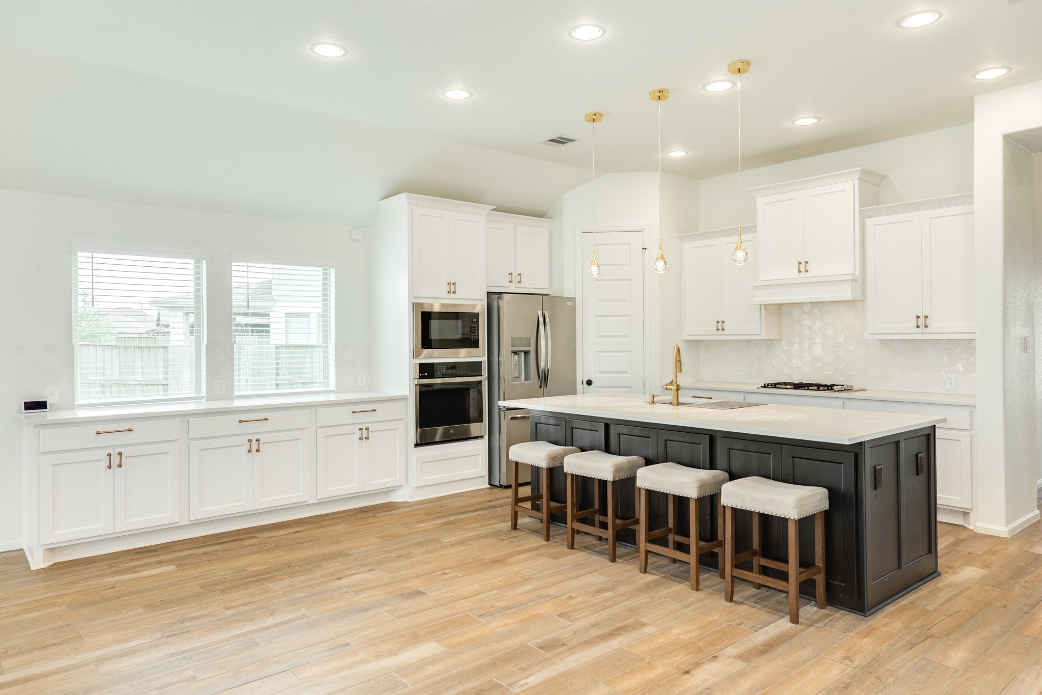 10115 Stride Court Rosharon, TX 77583 - Photo 7 of 40 Chef's dream kitchen featuring a large island with convenient under-counter storage and elegant gold trim accents. The space is highlighted by unique, custom jellyfish-inspired light fixtures hanging over the breakfast bar.