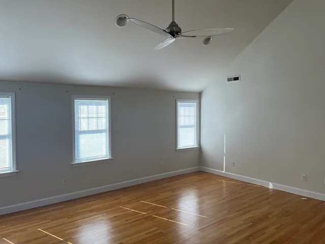a view of an empty room with wooden floor and a window