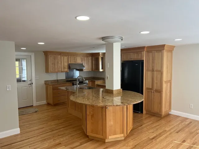 a kitchen with stainless steel appliances granite countertop a sink a stove and a wooden floors