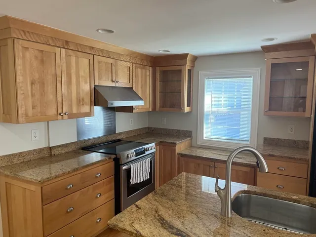 a kitchen with granite countertop a stove a sink and a microwave