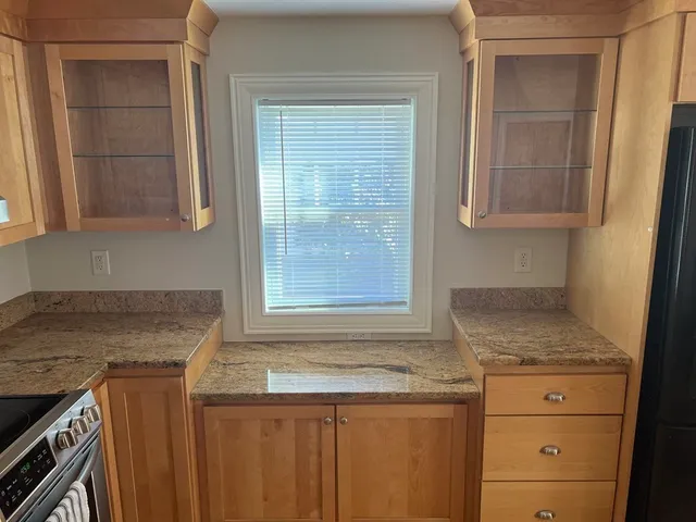 a kitchen with granite countertop cabinets stainless steel appliances and a window