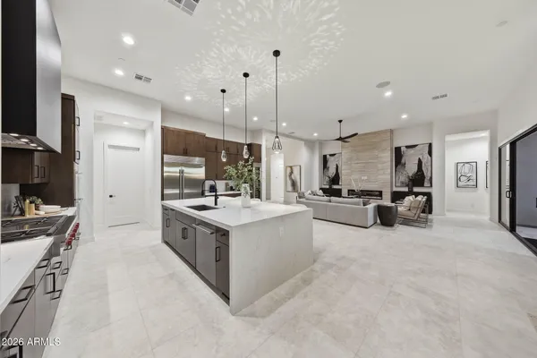 a large white kitchen with a large counter top a stove a sink and a refrigerator