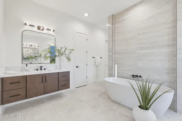 a bathroom with a double vanity sink a large mirror and a bathtub
