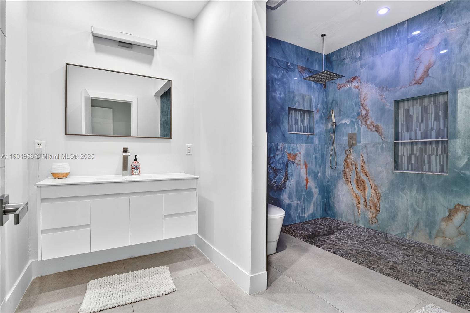 2325 Northeast 194th Street Miami, FL 33180 - Photo 25 of 36 a bathroom with a sink a mirror and a shower