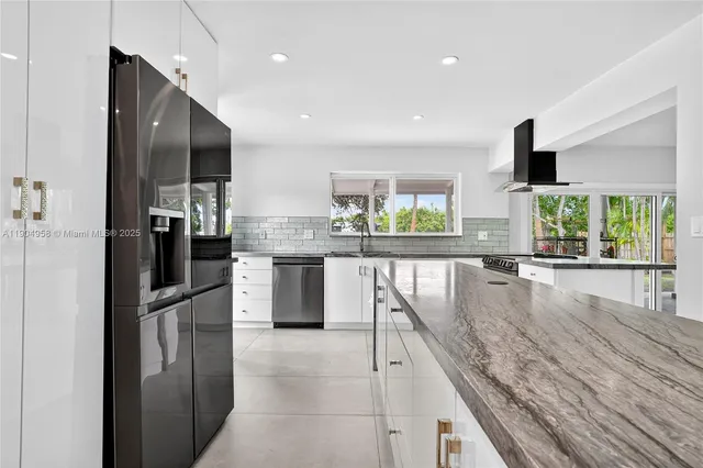 a kitchen with stainless steel appliances granite countertop a refrigerator and a view of living room