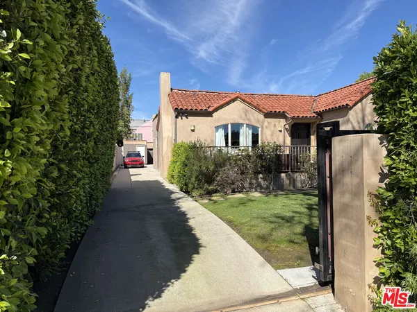 a view of a house with a small yard plants and a fountain
