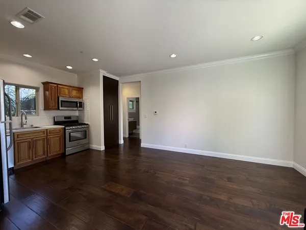 a view of kitchen with granite countertop stainless steel appliances and wooden floor