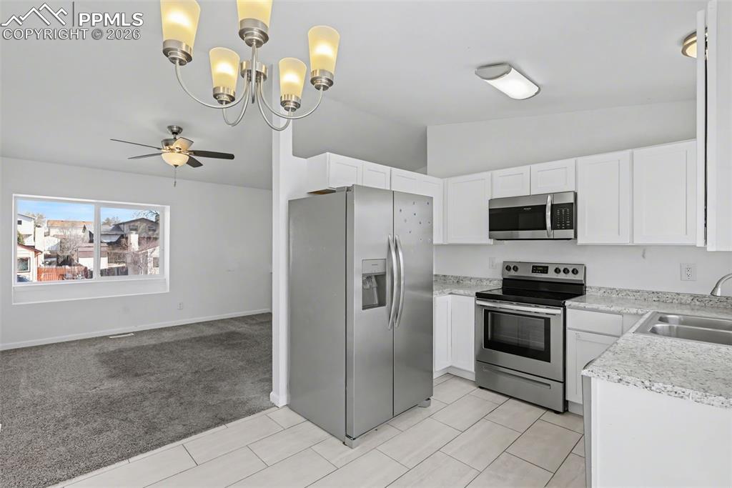 585 Blossom Field Road Fountain, CO 80817 - Photo 12 of 37 a kitchen with stainless steel appliances granite countertop a refrigerator a stove a microwave oven with white cabinets