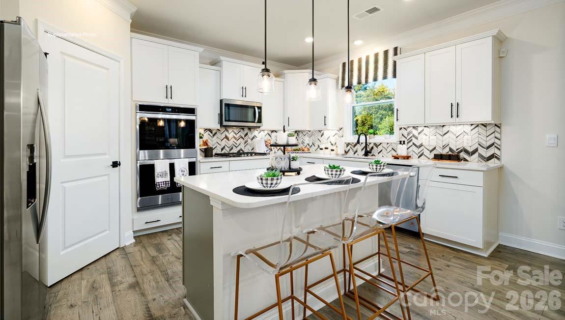 3111 Spring Iris Drive Denver, NC 28037 - Photo 4 of 44 a kitchen with stainless steel appliances a sink a stove a refrigerator cabinets and a window