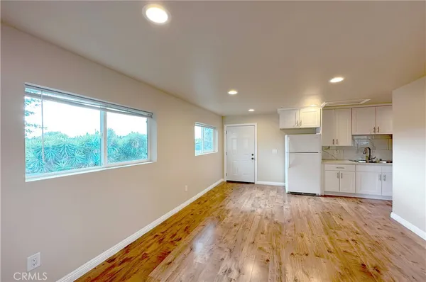a view of a kitchen with a fridge and wooden floor