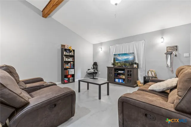 a living room with furniture a flat screen tv and a lamp