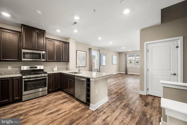 a kitchen with stainless steel appliances granite countertop a stove top oven a sink dishwasher a refrigerator and cabinets with wooden floor