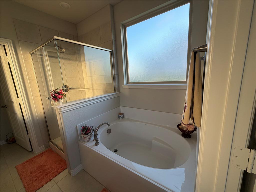 131 Llanos Drive Decatur, TX 76234 - Photo 8 of 9 Built-in soaking tub with deck-mounted faucet, adjacent walk-in shower with clear glass enclosure and tile surround, and frosted privacy window