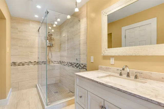 a bathroom with a granite countertop sink mirror and shower