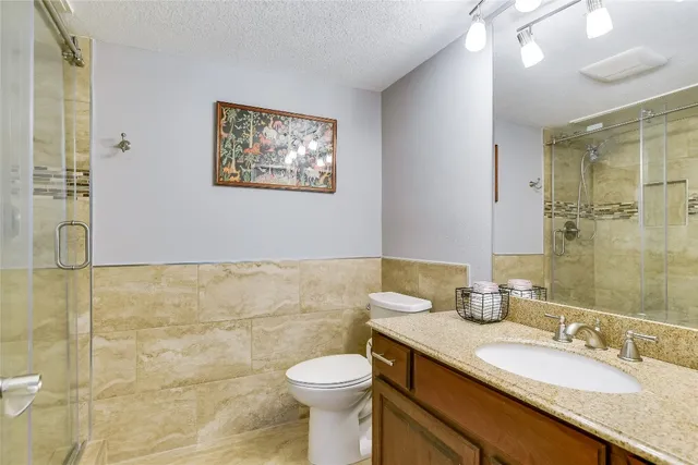 a bathroom with a granite countertop toilet sink and mirror