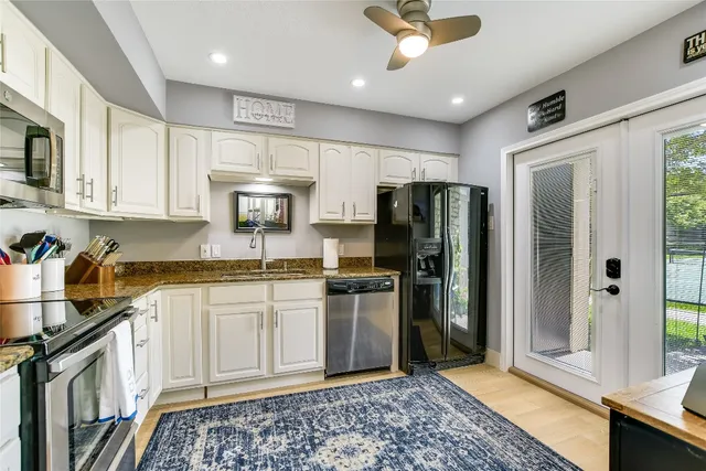 a kitchen with stainless steel appliances granite countertop a refrigerator a stove and a sink