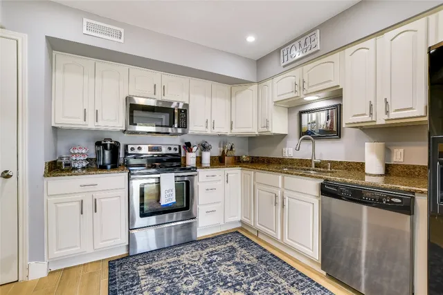 a kitchen with stainless steel appliances granite countertop a refrigerator a sink a stove a microwave and cabinets