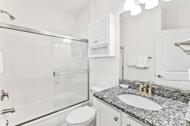 a bathroom with a granite countertop sink toilet and shower
