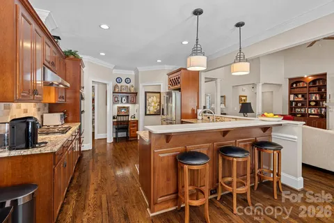 a kitchen with stainless steel appliances granite countertop a kitchen island a stove and a wooden floors