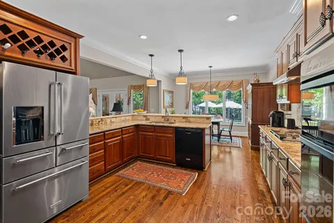 a kitchen with stainless steel appliances granite countertop a refrigerator a sink dishwasher a stove and white countertops with wooden floor