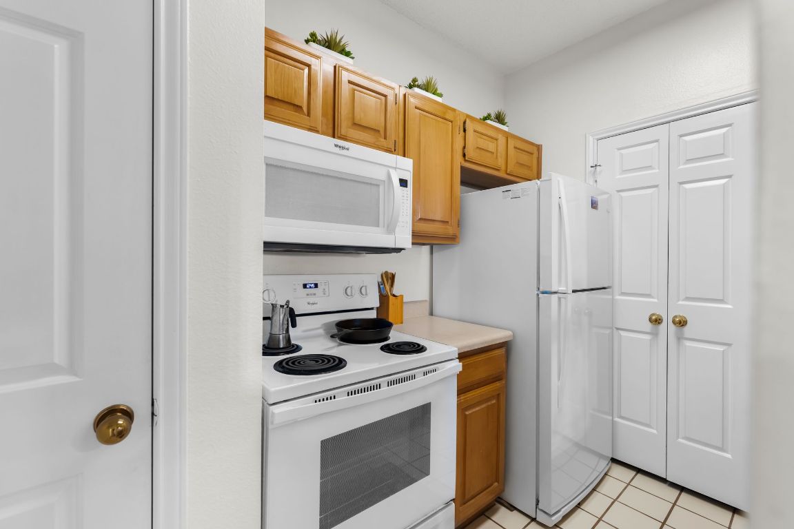 3001 Cedar Street, Unit 310 Austin, TX 78705 - Photo 11 of 27 a kitchen with stainless steel appliances a refrigerator stove and white cabinets