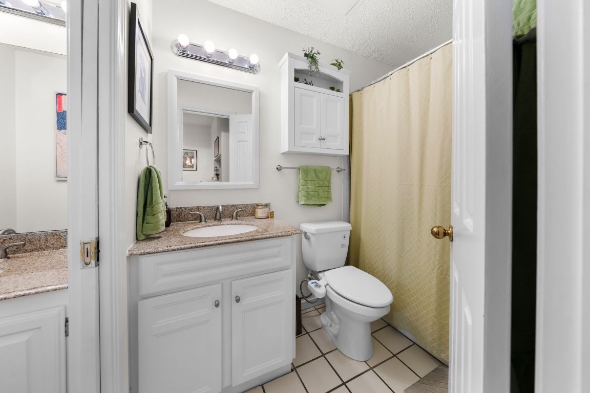 3001 Cedar Street, Unit 310 Austin, TX 78705 - Photo 19 of 27 a bathroom with a granite countertop sink a toilet and a mirror