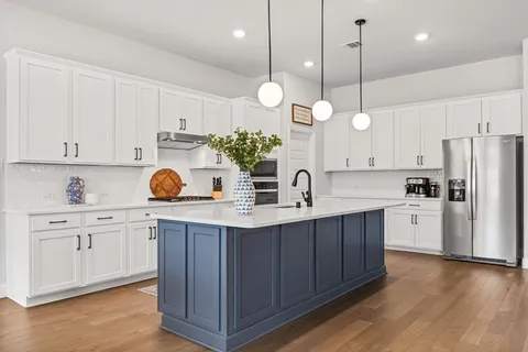 a kitchen with a sink a center island cabinets and stainless steel appliances