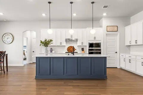 a kitchen with stainless steel appliances granite countertop a sink a stove and a wooden floors