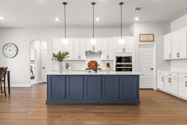 a kitchen with stainless steel appliances granite countertop a sink a stove and a wooden floors