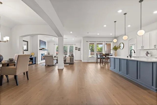 a living room with furniture kitchen view and a wooden floor