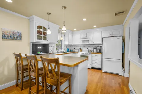 a kitchen with stainless steel appliances granite countertop a dining table chairs refrigerator and microwave
